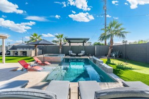 Una piscina con sillones de descanso y una zona de estar techada.