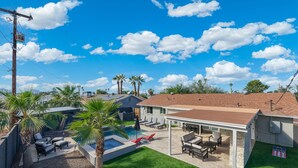 A residential backyard with a swimming pool, patio furniture, and palm trees. - PuttPutt, Outdoor TVs & BBQ Bar, Pool & Spa! 5 mins from Old Town! (Scottsdale)