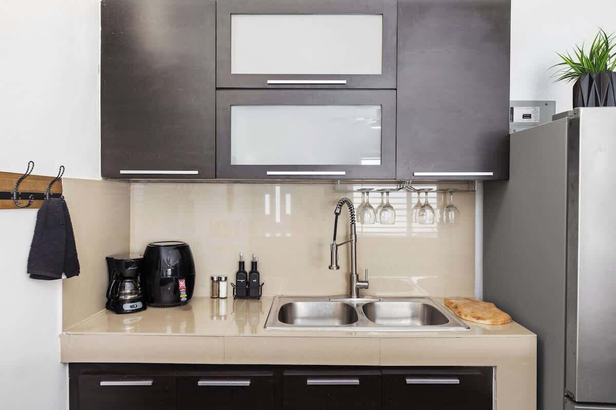 Una cocina moderna con un lavamanos doble, electrodomésticos de acero inoxidable y una cafetera.
