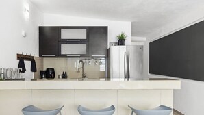 Una cuina moderna amb una illa central, electrodomèstics d'acer inoxidable i un disseny minimalista.