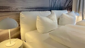 Una camera da letto moderna con un divano bianco, una lampada e un murale raffigurante una spiaggia.