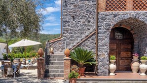 Un edificio de piedra con una puerta de madera, escalones que llevan a un porche y mobiliario exterior con una mesa y sillas.