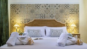 Una cama bien tendida con sábanas blancas, dos almohadas y una lámpara de noche.