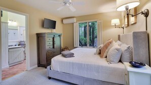 A bedroom with a bed, bedside lamps, a ceiling fan, a TV, and a window with shutters. - Wooded Lakeside adventure, walk to dock, 4 kid kayaks, screened porch, ping pong (Pocono Lake)