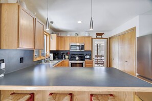 A modern kitchen with wooden cabinets, stainless steel appliances, and a large island.