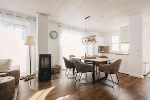 A modern kitchen with white cabinets, a wooden dining table, and a built-in stove.