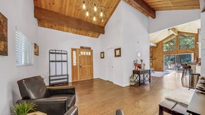 Un salon spacieux doté de planchers en bois, d’un plafond haut et d’une grande fenêtre offrant une vue sur l’extérieur.