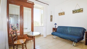 Quarto com armário de madeira, sofá azul, mesa redonda pequena e uma cadeira.