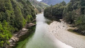 Um rio serpenteando por uma região montanhosa, com vegetação densa em ambas as margens.