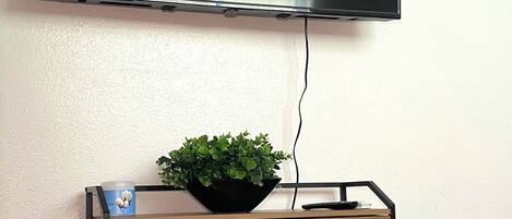 Un téléviseur à écran plat fixé au mur, au-dessus d’un meuble en bois doté de tiroirs.