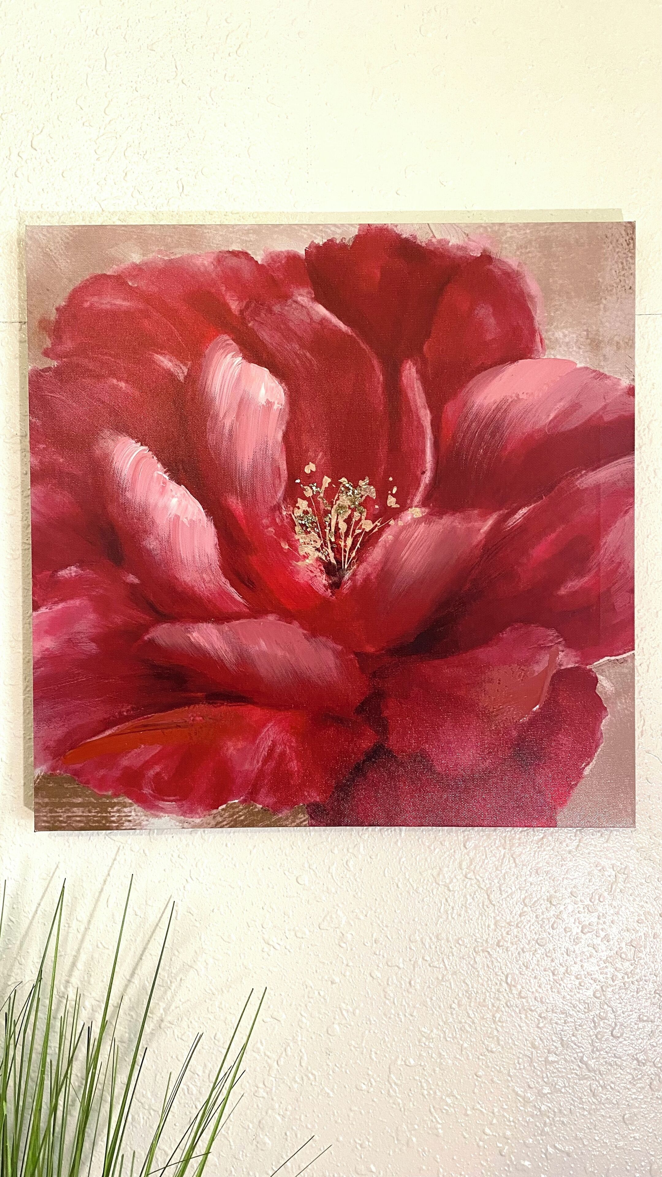 Een schilderij van een rode bloem op een structuurrijke muur.