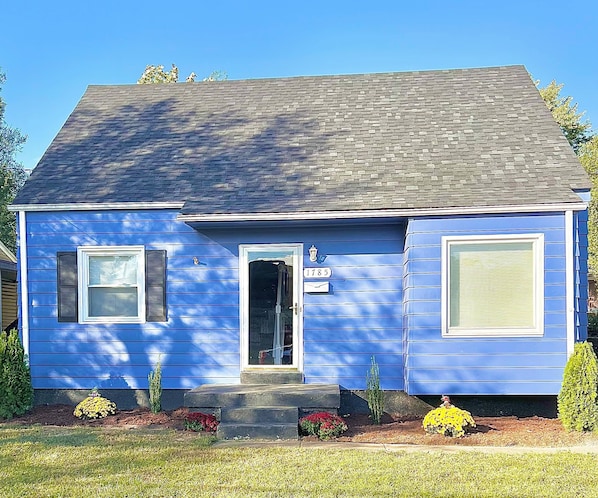 A two-story house with a blue exterior, a front door, and a mailbox.
