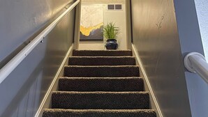 Eine Treppe mit Teppichstufen, einem Geländer und einem kleinen Topfpflanzen am oberen Ende.