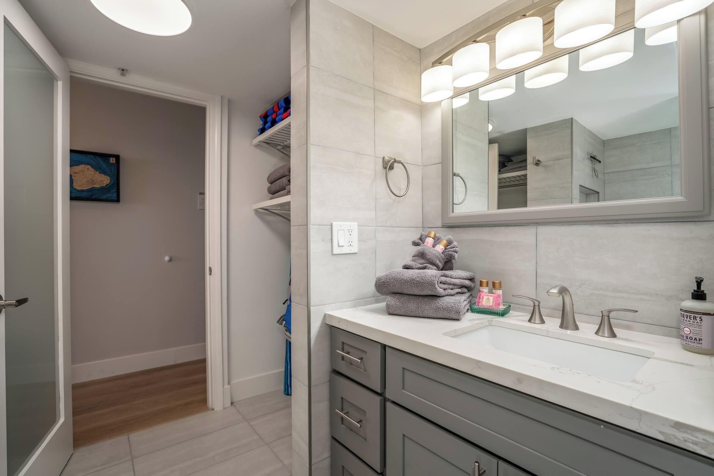 A modern bathroom with a large mirror, a sink with three faucets, and a towel rack.