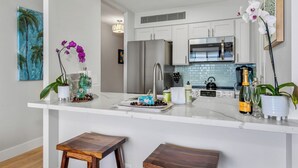 Een moderne keuken met witte kasten, roestvrijstalen apparatuur en een marmeren aanrecht.