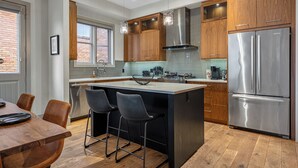 Una cocina moderna con armarios de madera, electrodomésticos de acero inoxidable y una isla central con taburetes de bar.
