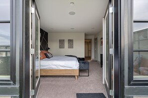 A modern bedroom with a bed, bedside tables, and a view through a glass door. - *Rare find* Calgary’s Finest |Cozy and Vibrant Double King Beds|Stampede Special (Calgary)