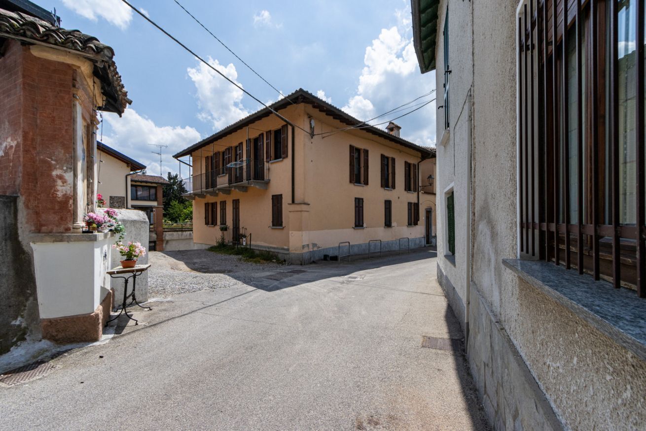 Une rue étroite, bordée de bâtiments des deux côtés, avec un chemin en béton et un ciel dégagé.
