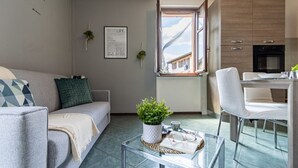 Ein modernes Wohnzimmer mit einer Couch, einem Couchtisch und Blick durch ein Fenster nach draußen.