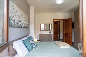 A bedroom with a bed, a dresser, a mirror, and a door leading to another room. - [SMART FLAT] Apartment whit Private Garage, Free Wi-Fi (Castelletto sopra Ticino)