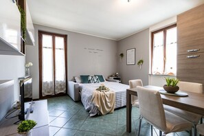 Une chambre à coucher de taille réduite, comprenant un lit, une table de chevet et un petit bureau avec une chaise.