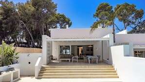 A modern house with a pool, outdoor seating, and a staircase leading to a covered patio.