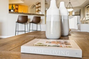 Un livre intitulé « Conçu pour la vie » est posé sur une table en bois dans une cuisine moderne, avec deux tabourets de bar et un coin repas en arrière-plan.