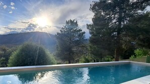 Una piscina con vistas despejadas a árboles cercanos y una lejanía de montañas.