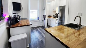Una cocina moderna con encimera de madera, electrodomésticos de acero inoxidable y horno empotrado.