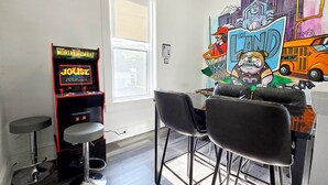 Una habitación con una máquina recreativa de Mortal Kombat Midway, una ventana y un mural de 'La Tierra de los Bulldogs'.