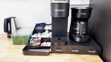 A coffee maker, a kettle, and a coffee pot on a wooden table.