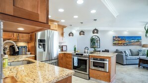 Eine moderne Küche mit Granit Arbeitsplatten, Edelstahlgeräten, Holzschränken und Pendelleuchten.