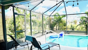 Un espace extérieur abrité comprenant une piscine, des chaises longues et une vue sur la verdure.