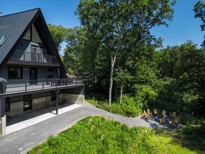 A modern two-story house with a balcony, surrounded by lush greenery. - Emberwood Lodge - Luxury Cabin, Kid Friendly (Catskill)