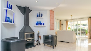 Una sala de estar moderna con chimenea, sillones de cuero negro y un sofá.