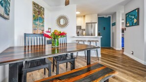 A modern kitchen with white cabinets, a stainless steel refrigerator, and a blue accent wall. - Modern and Relaxing Oceanfront Vistas (Kihei)