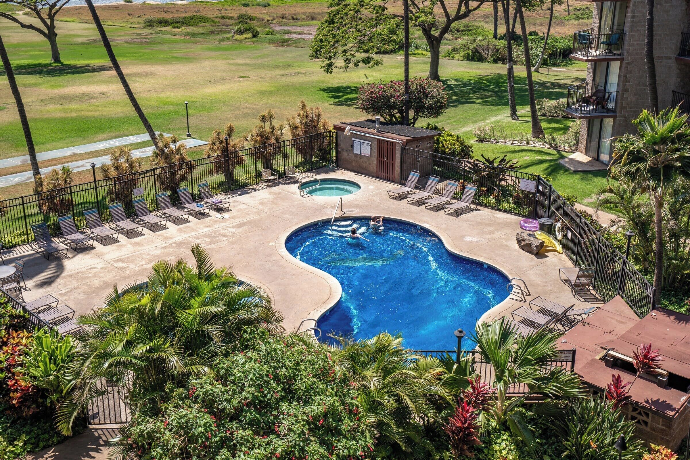 A pool area with two pools, sun loungers, and a small building.