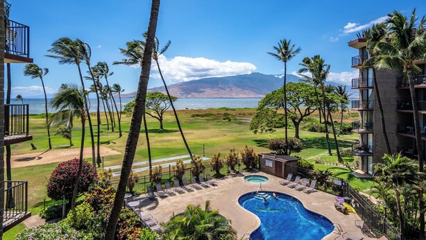 A hotel with a pool, palm trees, and a view of the ocean. - Modern and Relaxing Oceanfront Vistas (Kihei)
