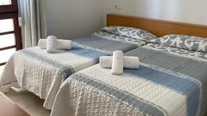 Ett hotellrum med två sängar, var och en med ett mönstrat överkast och kuddar, och ett fönster med gardiner.