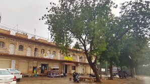 A building with a balcony, a signboard, and parked vehicles. - Berozgar Hostel (Jaisalmer)