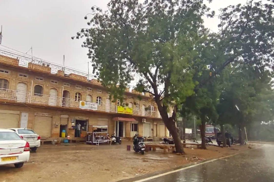 A building with a balcony, a signboard, and parked vehicles.