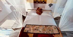 Un lit avec du linge de lit blanc, une courtepointe et un coussin décoratif.