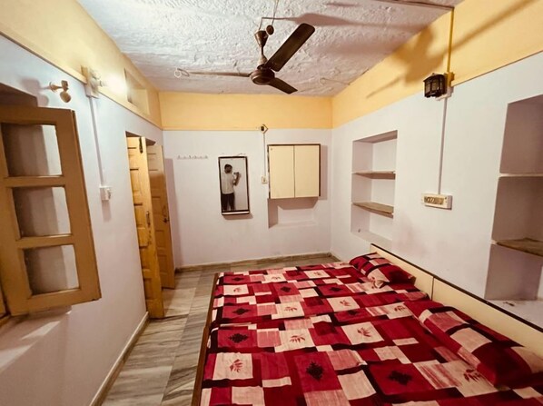 Une chambre à coucher avec un lit, un ventilateur de plafond, un miroir et une armoire.