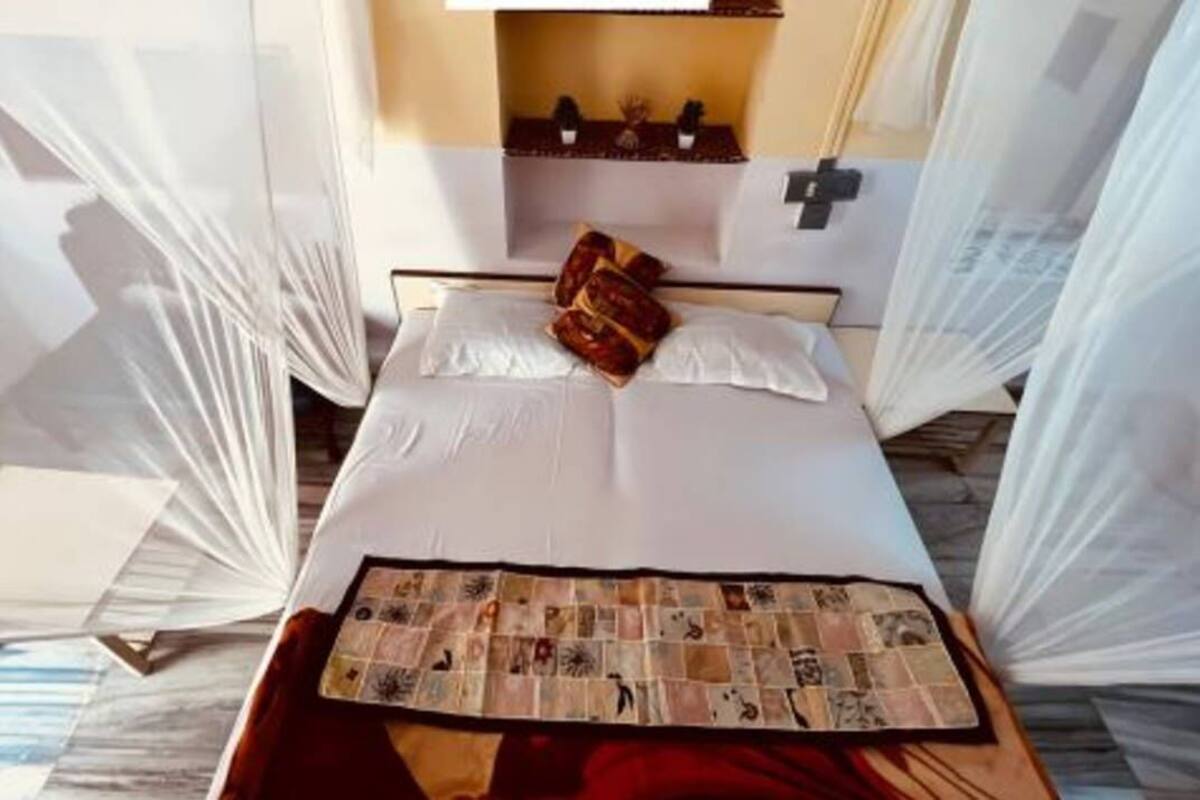 A neatly made bed with white linens, a decorative throw, and a small table with a magazine.