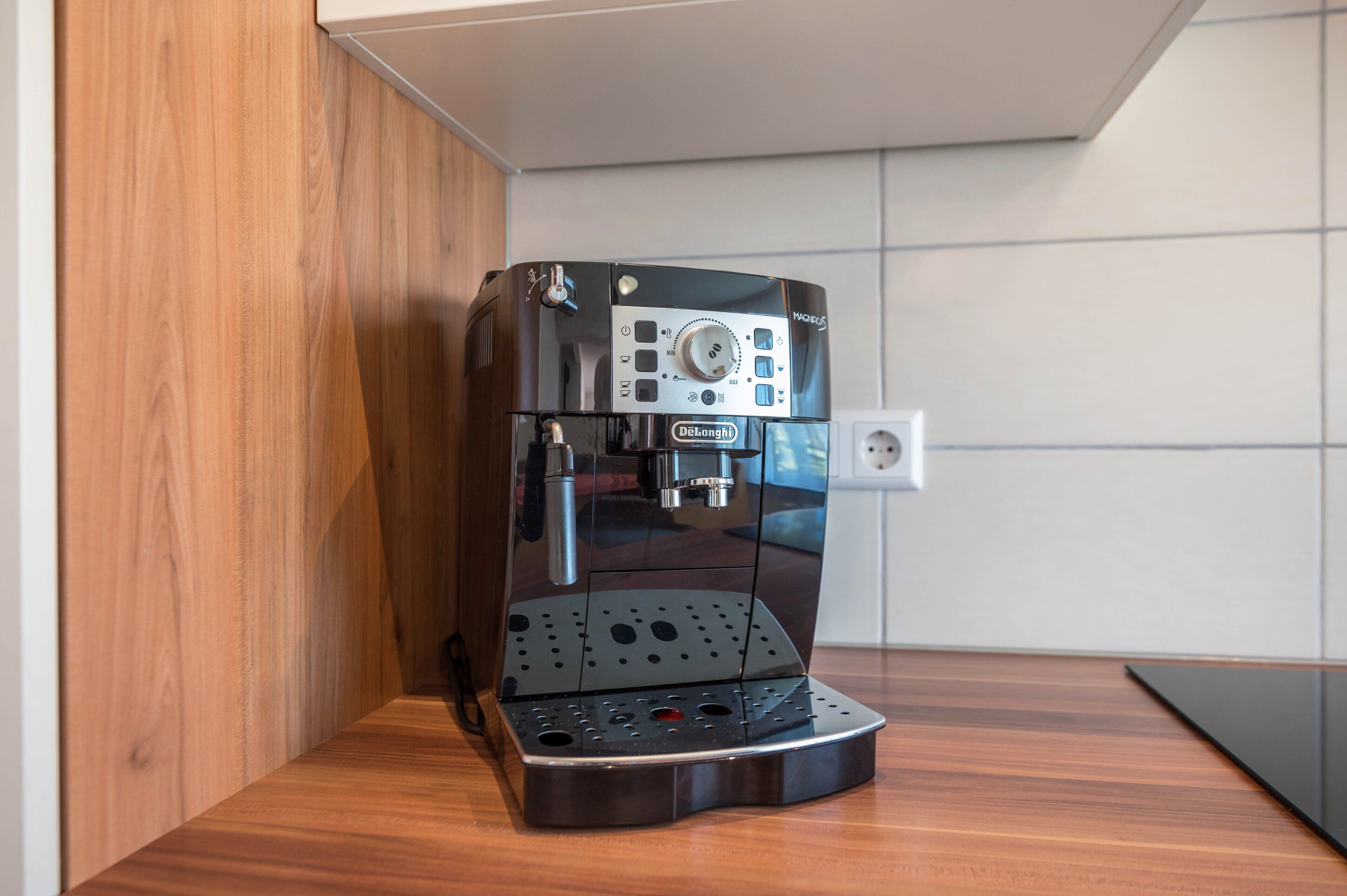 En moderne espressomaskine med digitalt display, placeret på en træbordplade i et køkken.