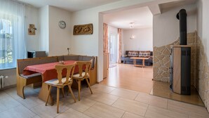 A dining area with a table and chairs, a clock on the wall, and a stone fireplace. - Apartment 'Haus Isele' with Mountain View, Terrace and Wi-Fi (Dachsberg)