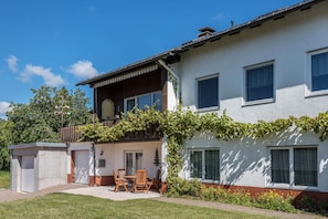 A two-story building with a balcony, a small garden, and a patio area with outdoor furniture. - Apartment 'Haus Isele' with Mountain View, Terrace and Wi-Fi (Dachsberg)