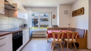 A compact kitchen with a dining area, a radiator, and a window with a view. - Apartment 'Haus Isele' with Mountain View, Terrace and Wi-Fi (Dachsberg)
