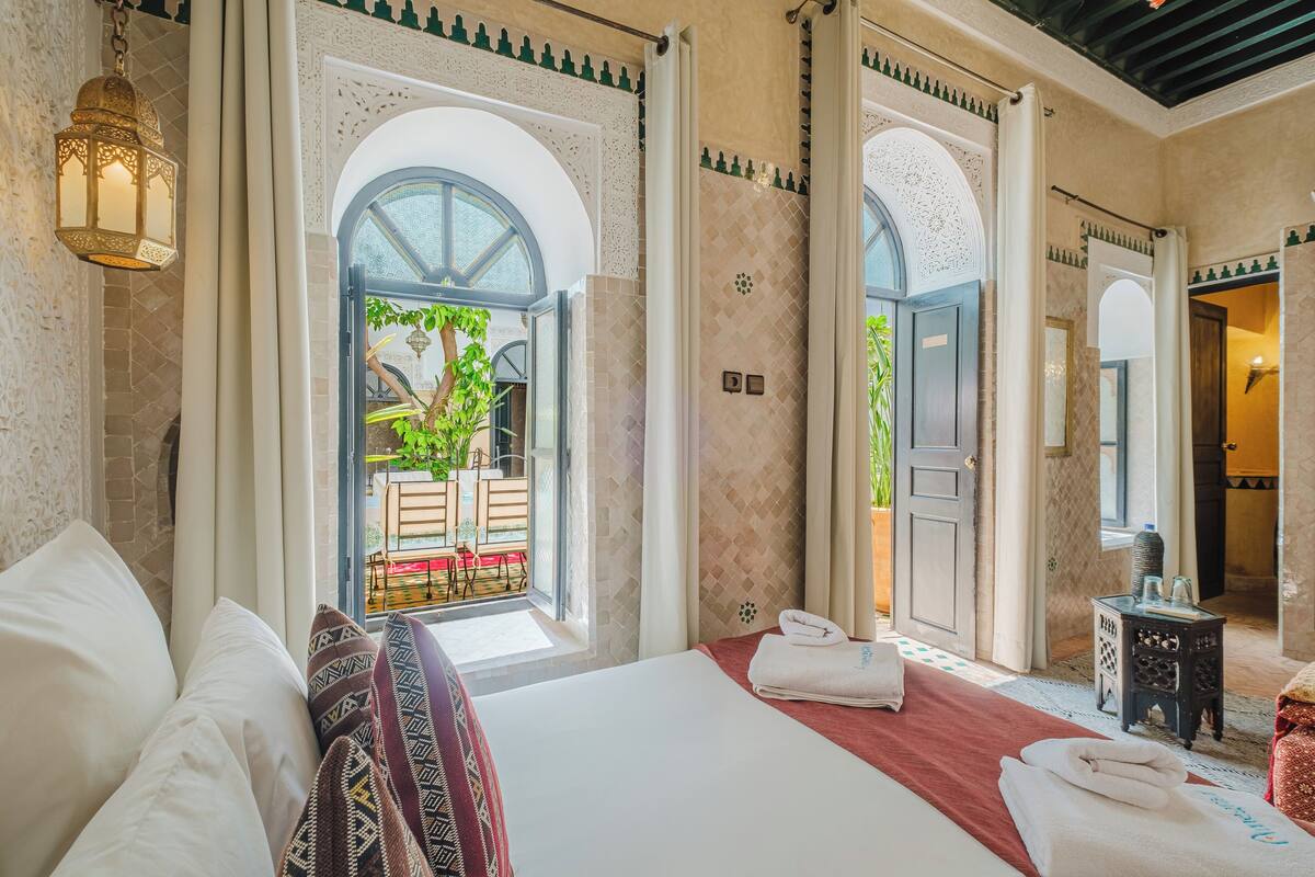 Une chambre d’hôtel avec un grand lit, une vue sur l’extérieur et une petite table avec une lampe.