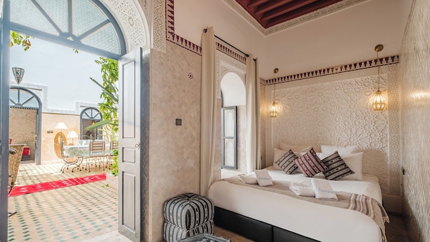 Un dormitorio amplio con una cama grande, un rincón de descanso y vistas al patio.